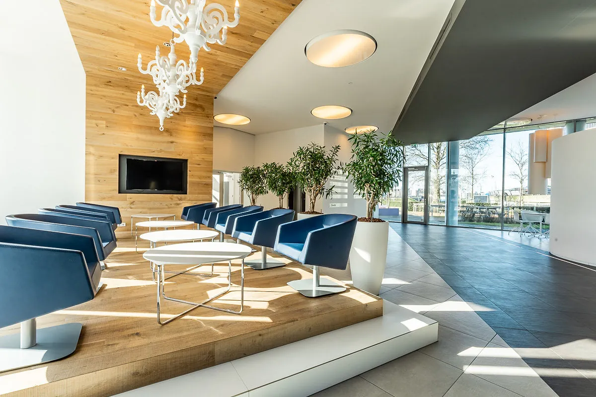 Moderne wachtruimte in Rivium Quadrant met blauwe stoelen, houten accenten en grote ramen met uitzicht.